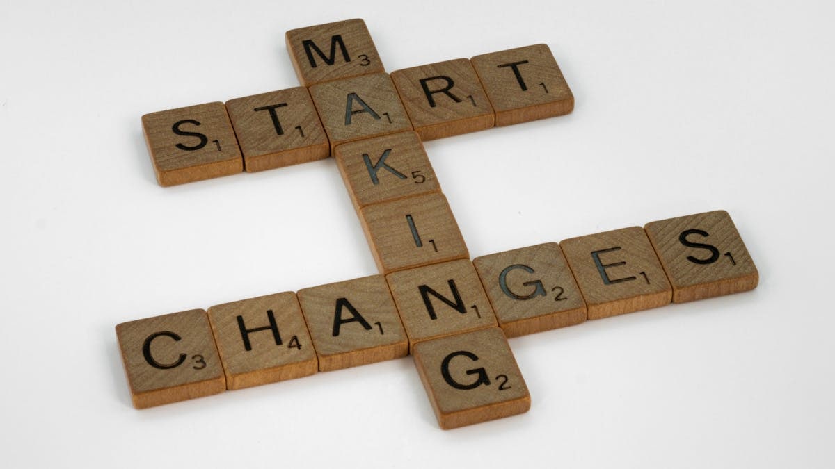 Top view of Scrabble tiles forming the phrase 'Start Making Changes' on a white background.